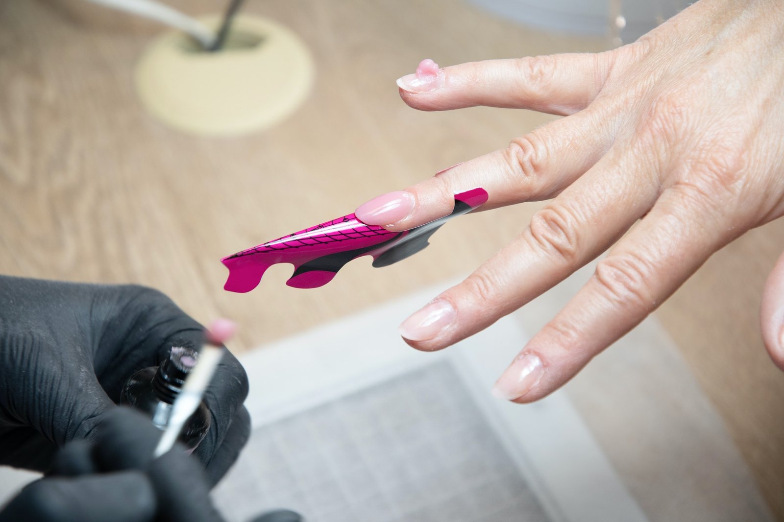 manicurist lengthens client's nails with acrylic builder gel sticker
